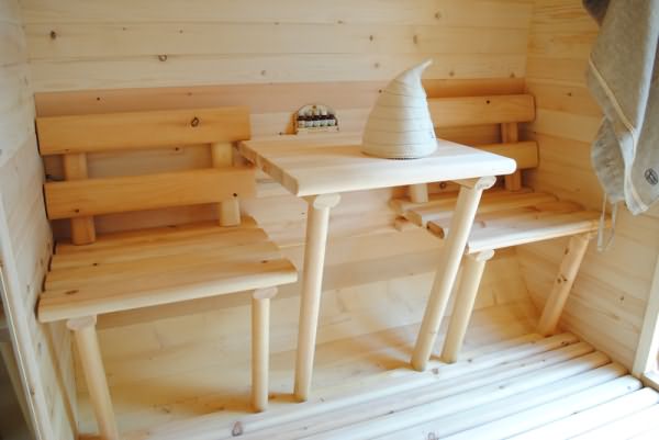 На фото изображен маленький предбанник с решетчатым деревянным полом в бане-бочке